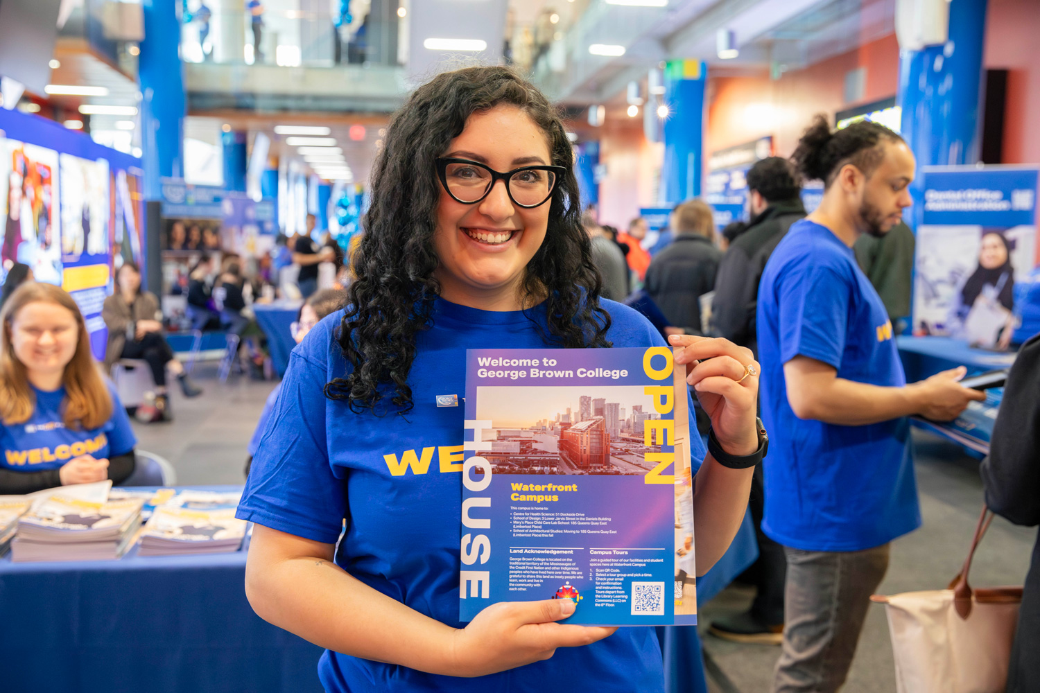 An ambassador at the open house holds up a campus guide.
