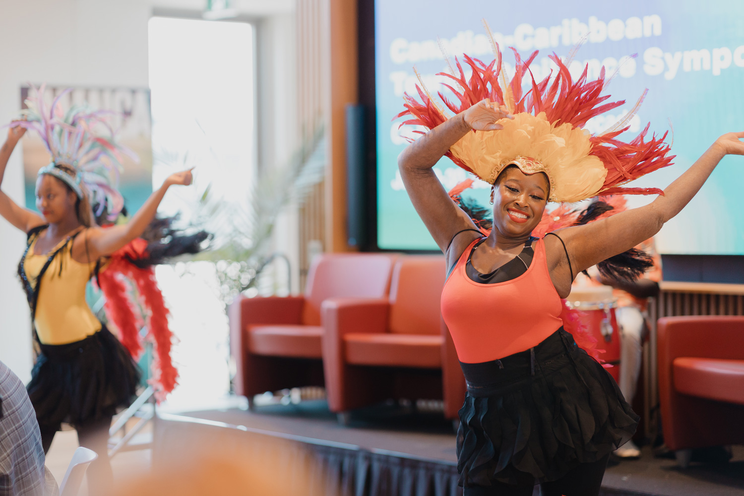 Performers with feather headresses dance and wave their arms at the Canadian Caribbean Tourism Resilience Symposium.