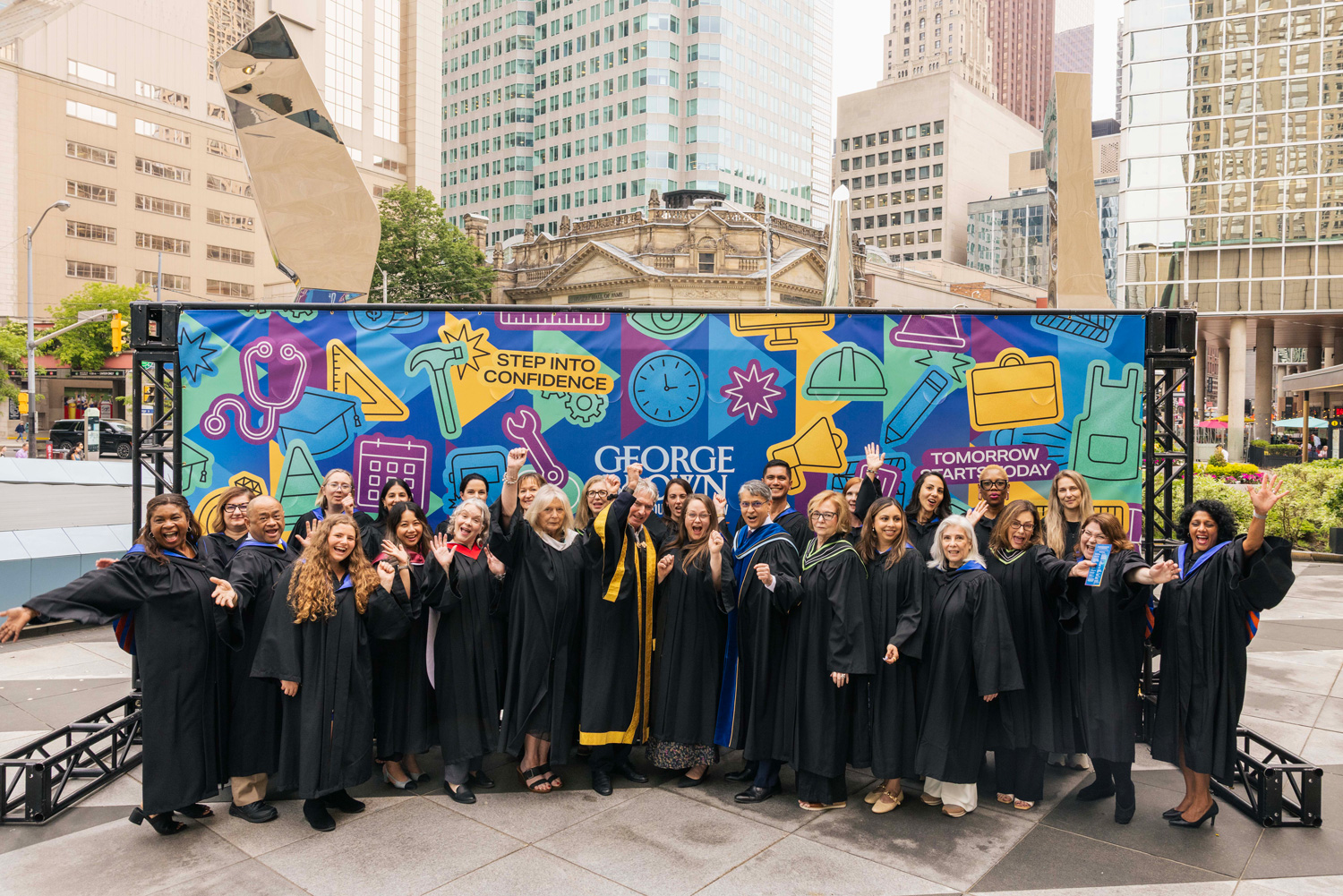 George Brown faculty and staff pose for a group shot at Convocation in front of this year's student mural.