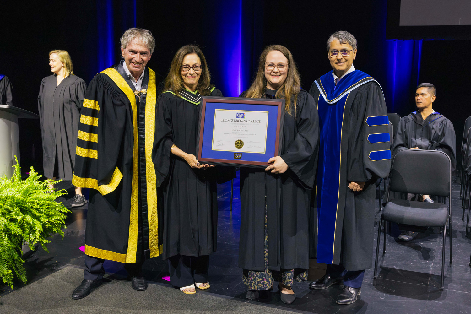 Dr. Malik, Chancellor Smith, and Dean Toews pose with honorary credential recipient Alana Powell at Convocation.