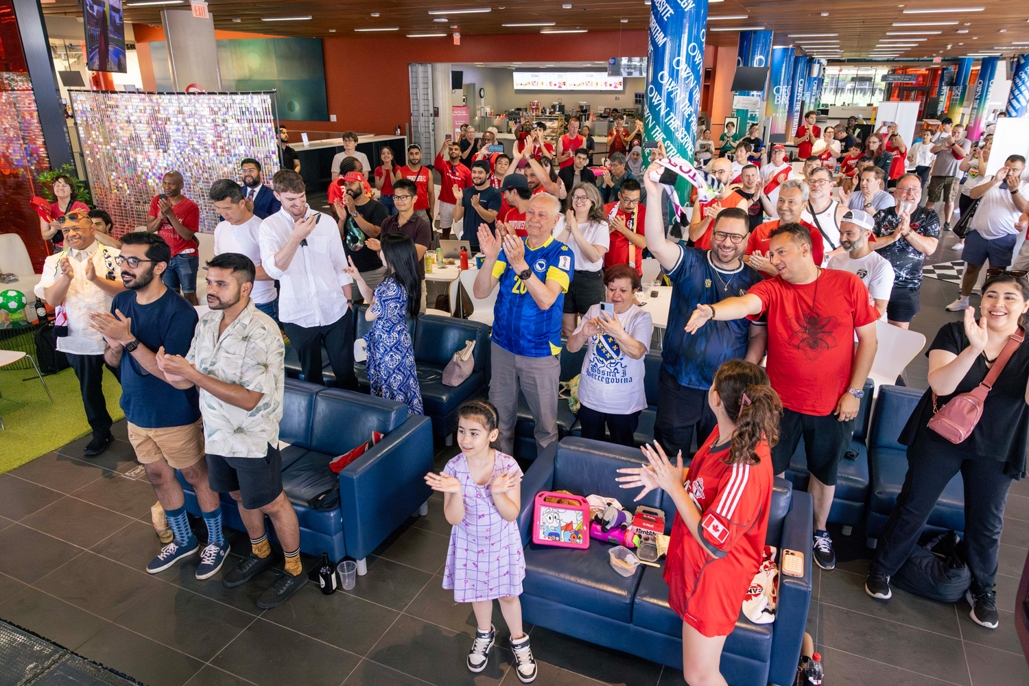 Guests at the FIFA Pride House stand and cheer for team Canada.