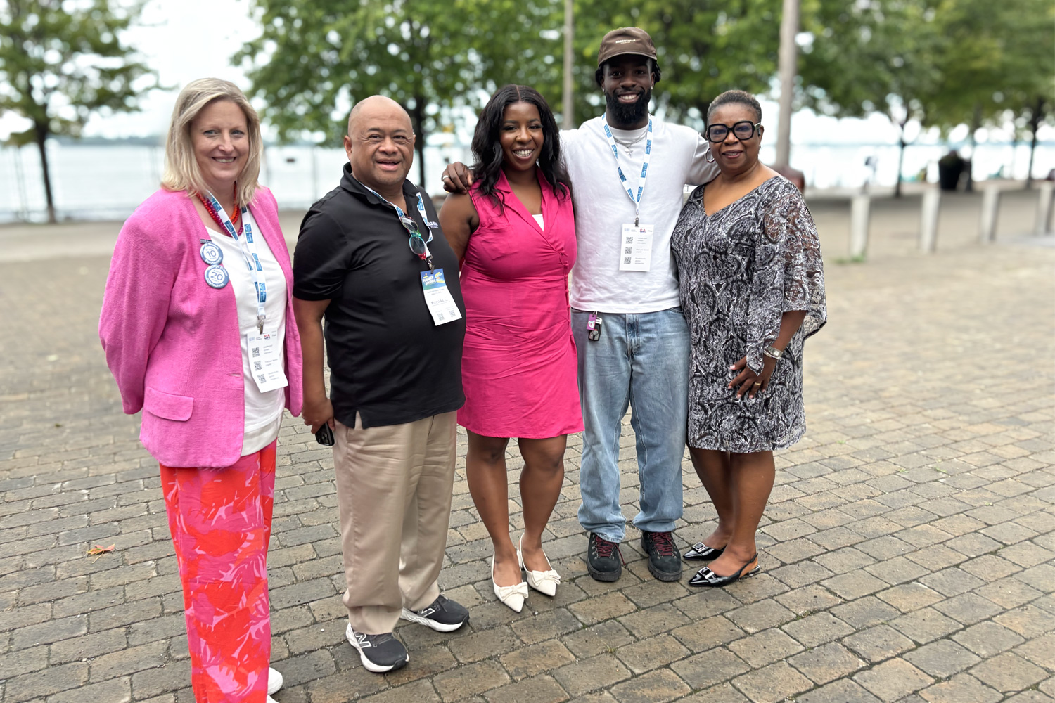 Keynote alumni speaker Simi Olatunji poses for a photo with George Brown leadership and guests outside with the lake and trees behind them.