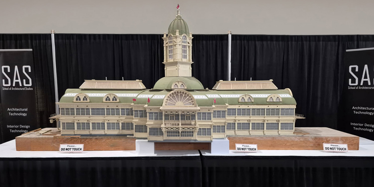 A scale model of the Crystal Palace that has undergone restoration by George Brown students with detailed ironwork and glass, green roof, and miniature Ontario flags.