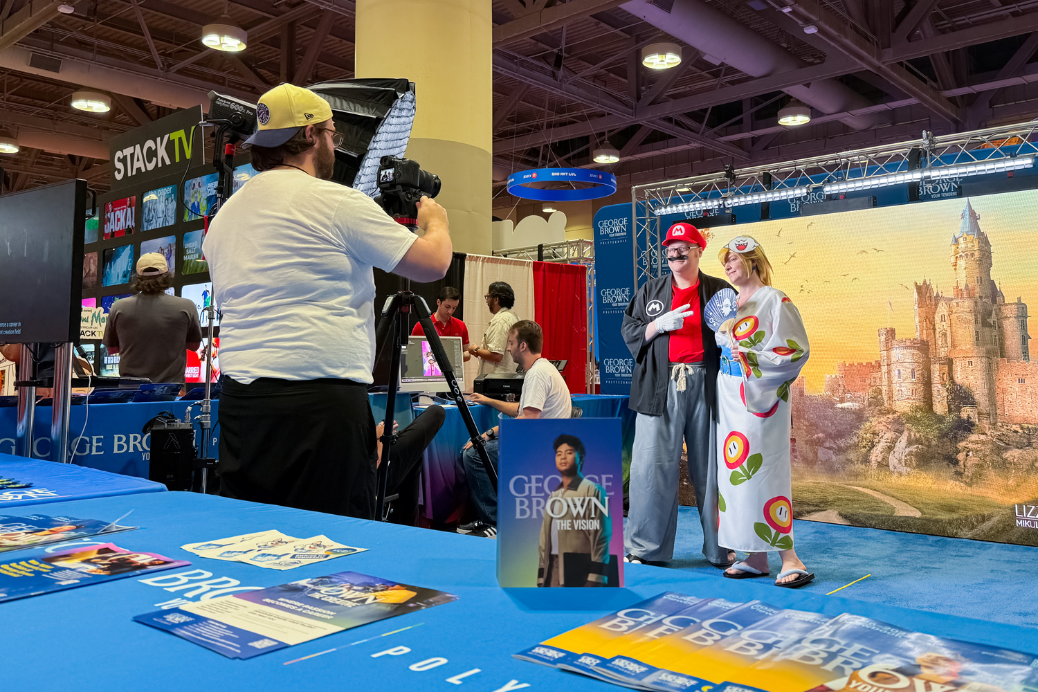 Two people in cosplay pose for a photo a George Brown's Fan Expo booth.