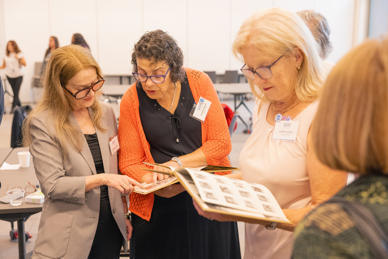 Nursing grads from 1976 look at yearbooks from their graduation at a reunion event held at Limberlost Place.