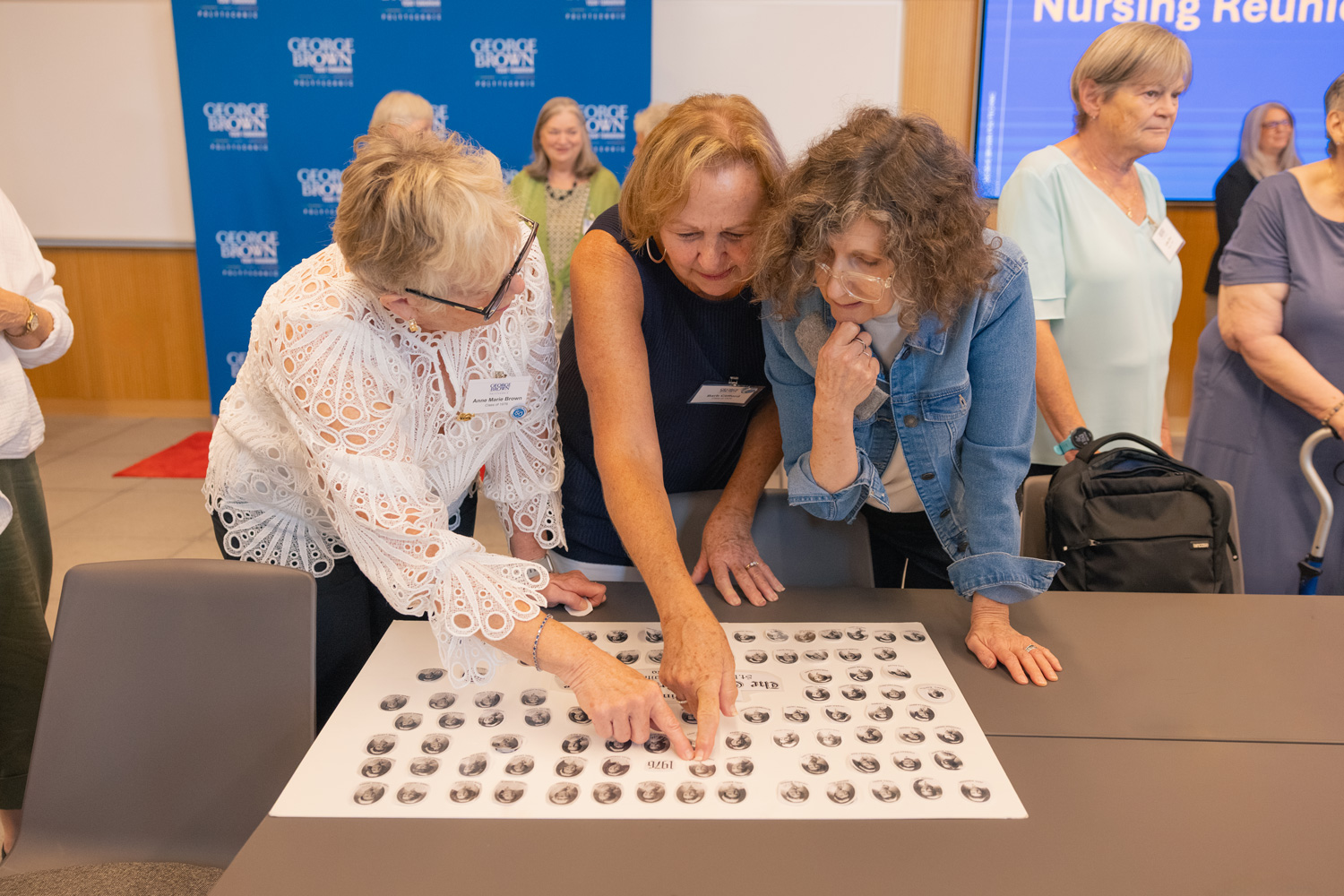 1976 Nursing grads look at photos from their graduation 50 years prior to the reunion event.