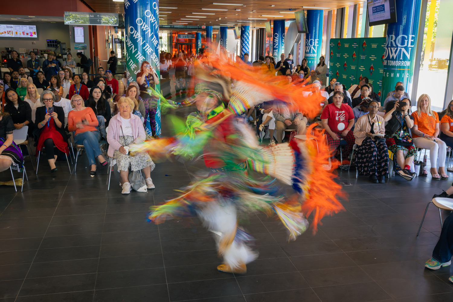 A member of the Mississaugas of the Credit performs a fancy dance at the Waterfront Campus in traditional clothing.