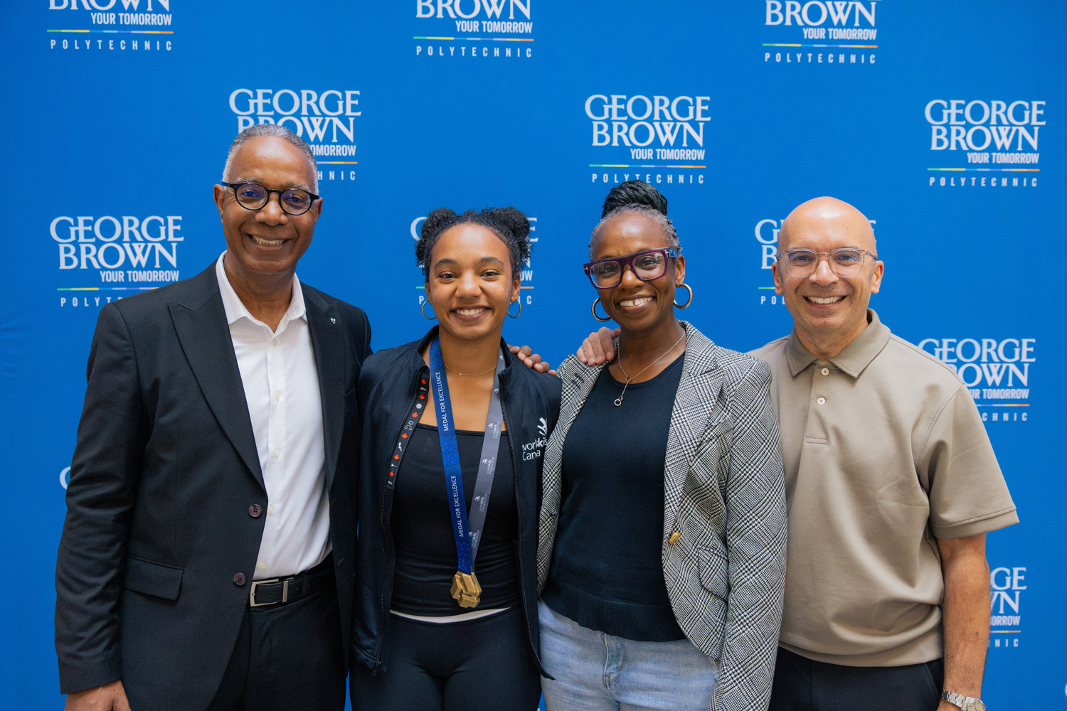 Luca poses for a photo with George Brown President Dr. Gervan Fearon and her parents.