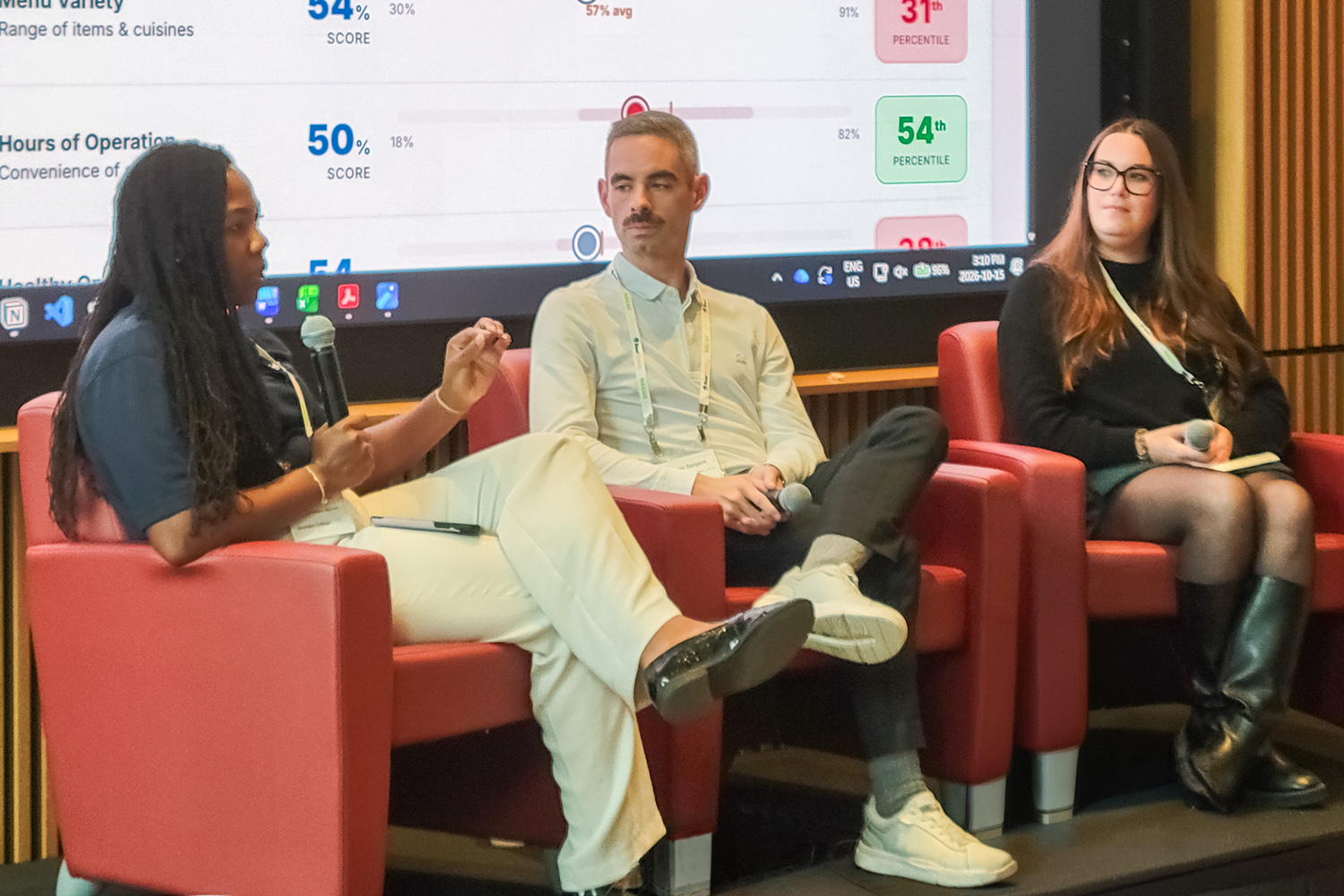Panelists at the NACAS conference sit in red chairs on a stage in front of a large screen discussing current challenges in the post-secondary sector.