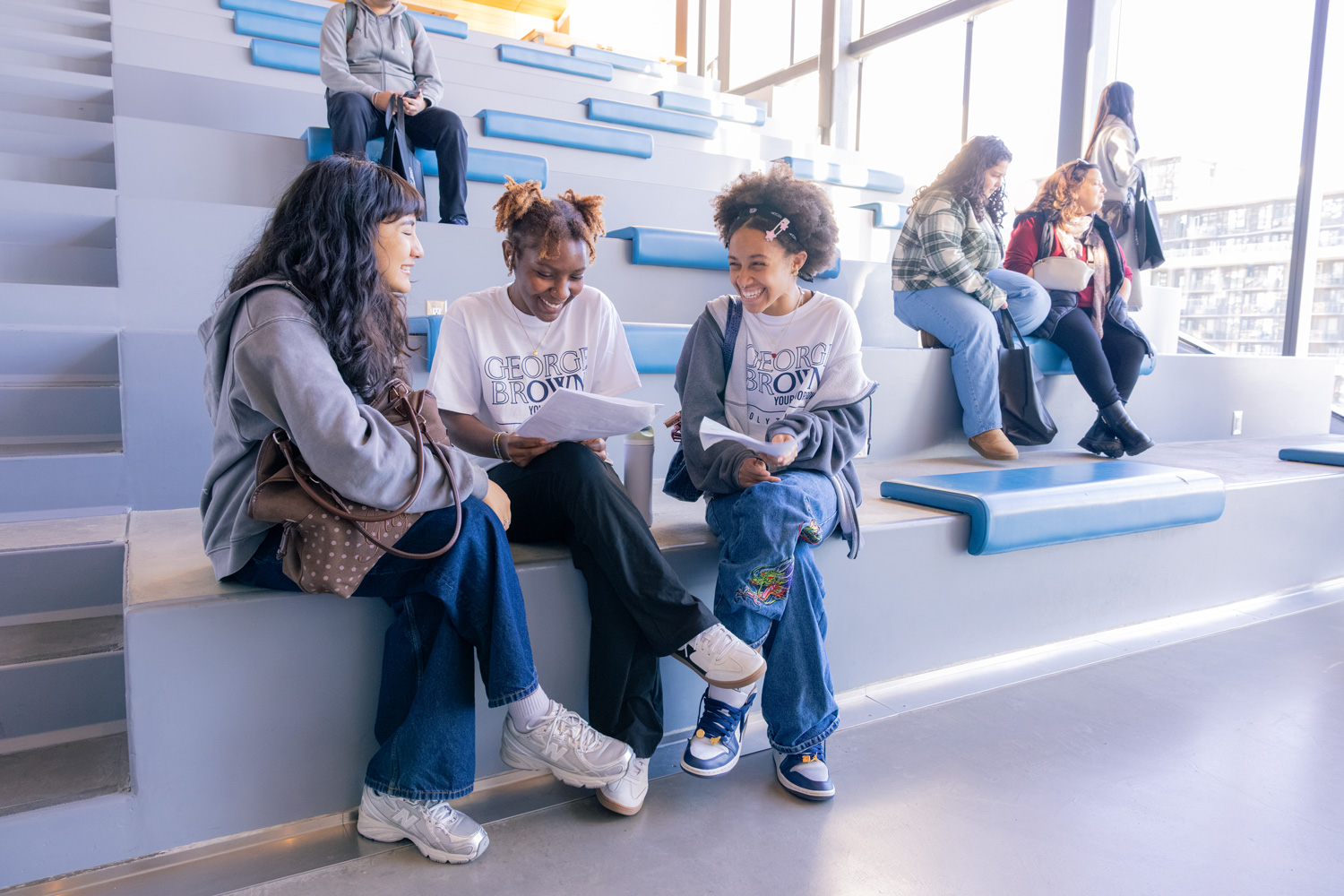 Three students are seated in a learning landscape at the Waterfront Campus chatting.