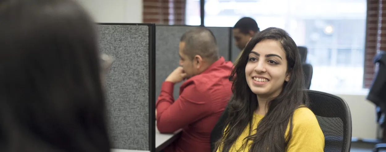 Female student in yellow sweater smiling at another student