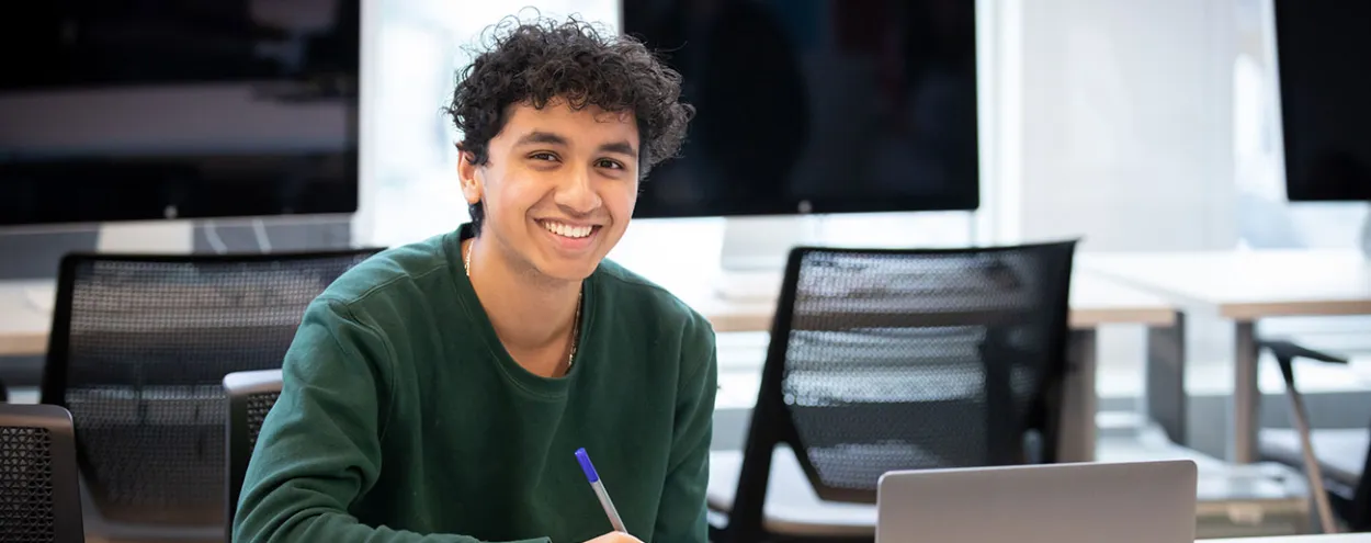 student with notepad and laptop