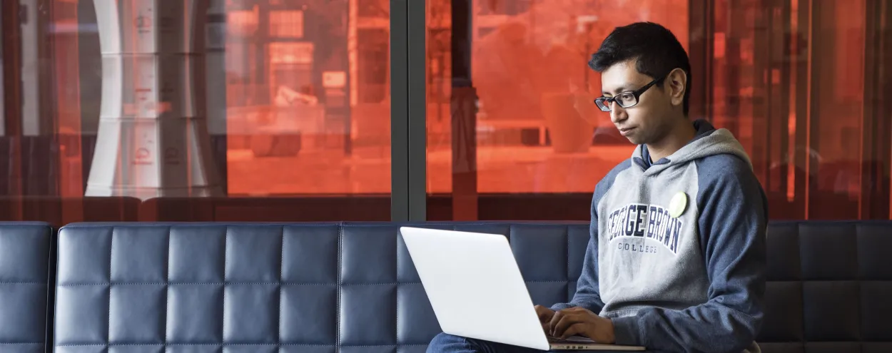 Student sitting on couch, using a laptop