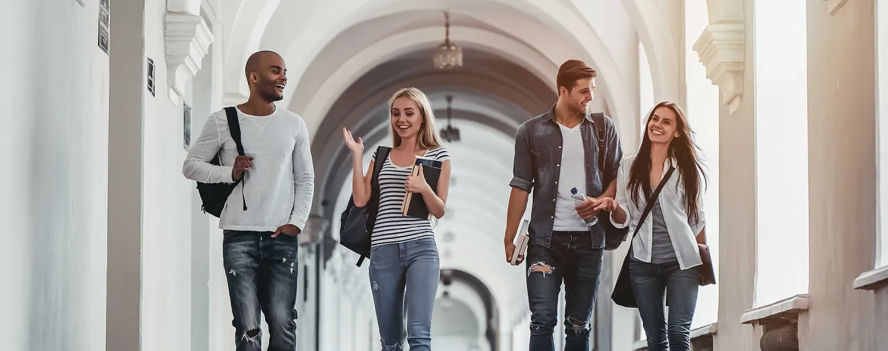 4 students walking together on a campus