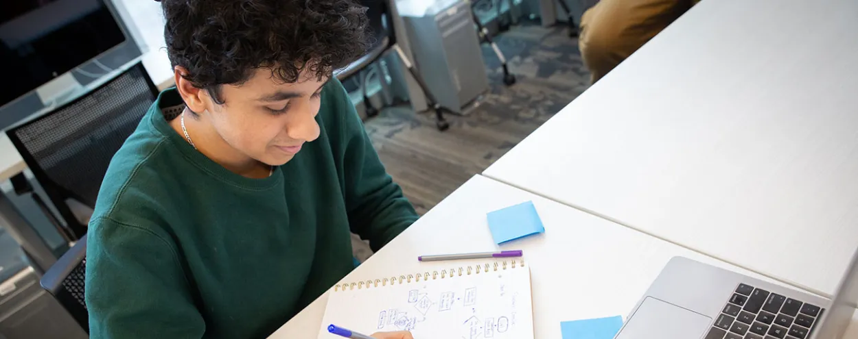 male student writing in notebook