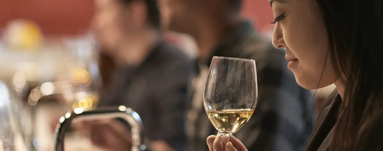 young Asian woman sniffing a glass of wine