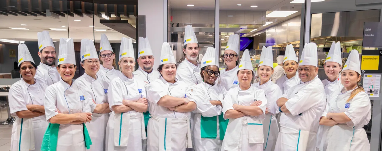 George Brown senior leaders pose together dressed in chef's whites as they help prepare holiday meals for students in need