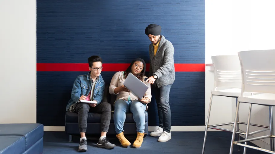 3 students looking at a laptop
