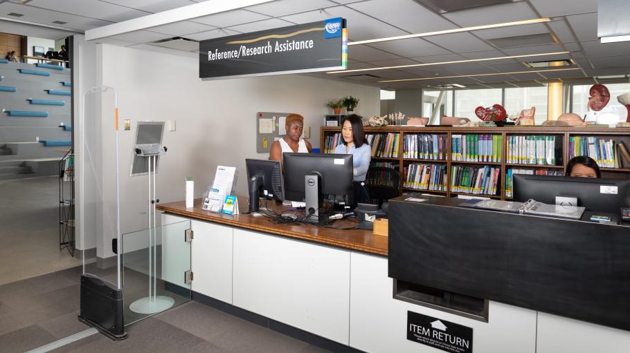 A student receiving help from one of the librarians at the Reference/Research Assistance Desk at the Waterfront Campus Library (LLC).
