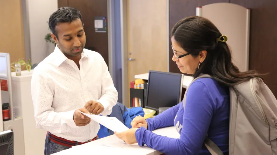 A student asks a question to one of the employees at a welcome desk.
