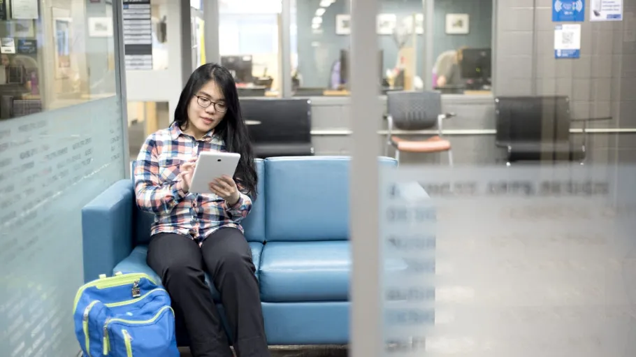 Female student sitting on a bench using a tablet