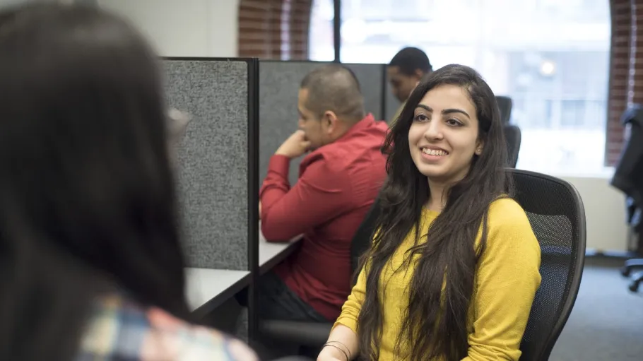 Female student in yellow sweater smiling at another student