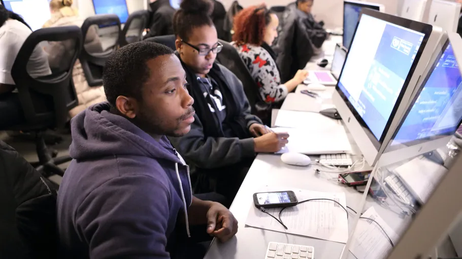 Students working in the library on the computers together. Group working environment.