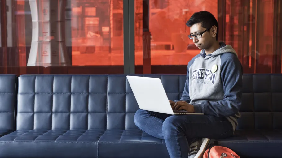 Student sitting on couch, using a laptop