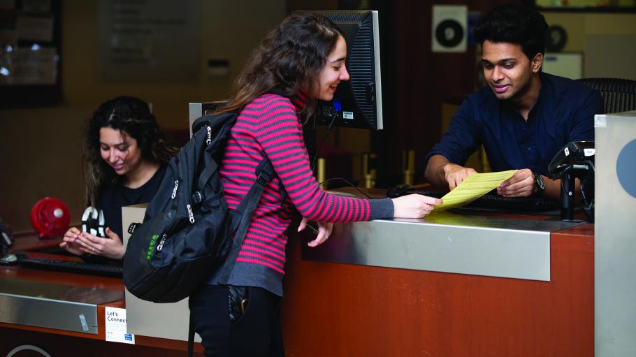 Female student speaking to a male Student Service Centre employee at the information desk.