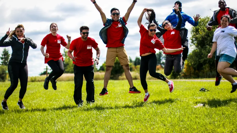 A group of students in red tshirts jump in the air.