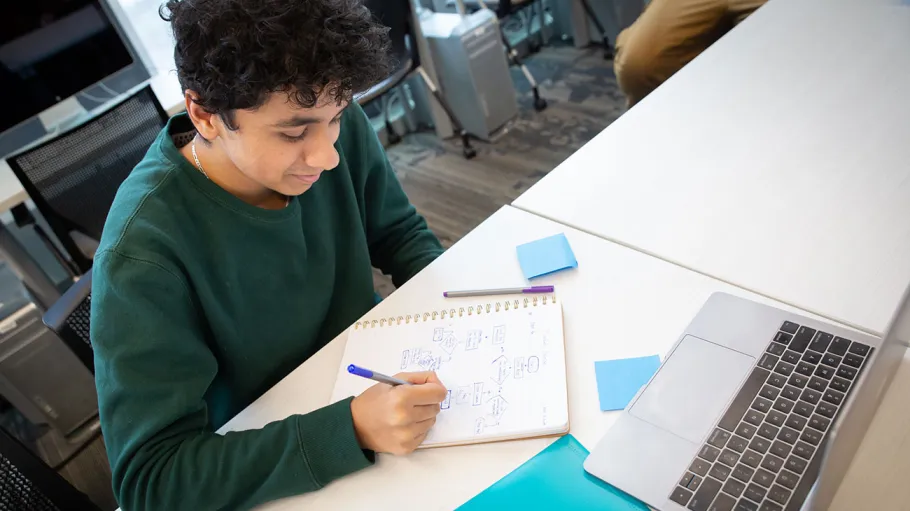 male student writing in notebook