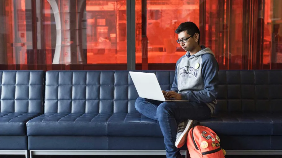 Male student with a laptop in the campus hall
