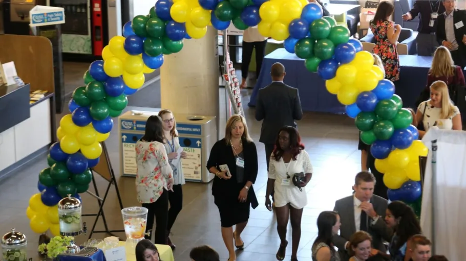 Group of people walking underneath a balloon arch at annual 5 to Watch Awards event