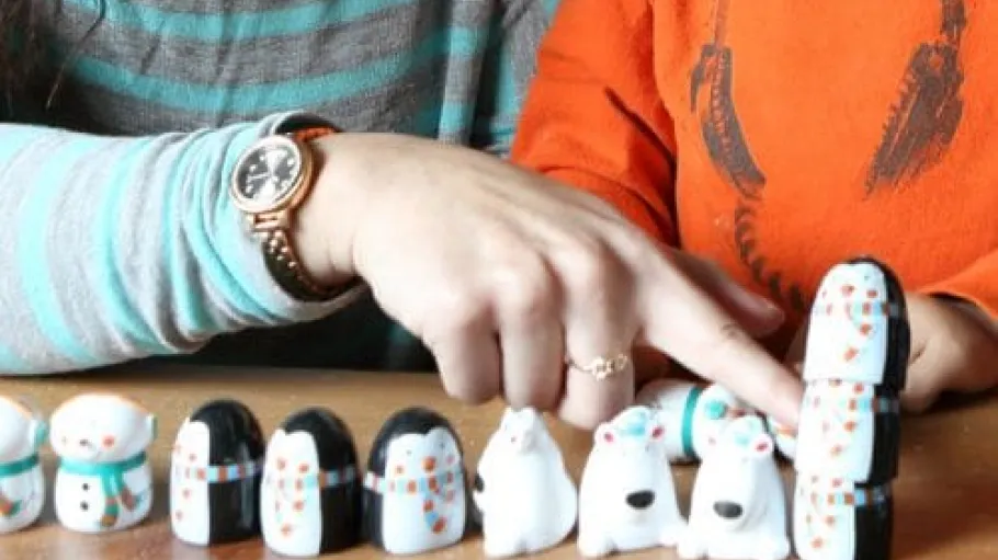 A mother and child looking at toys lined up from shortest to tallest.