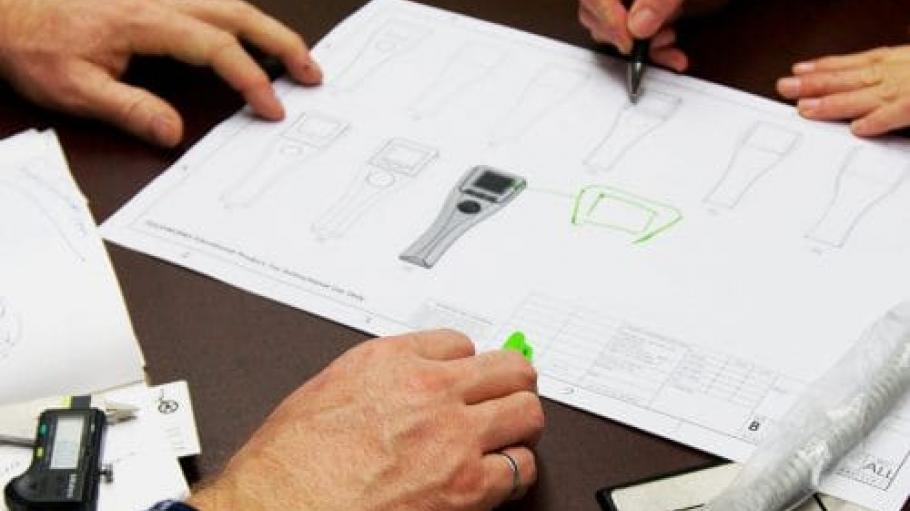Overhead shot of two people designing a product on graph paper