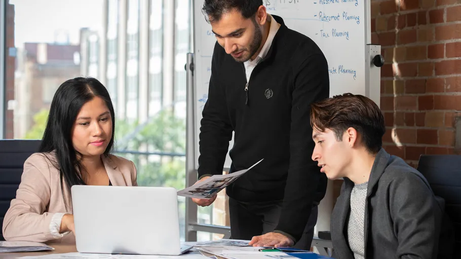 A photo of 3 business post-grads collaborating on a project.