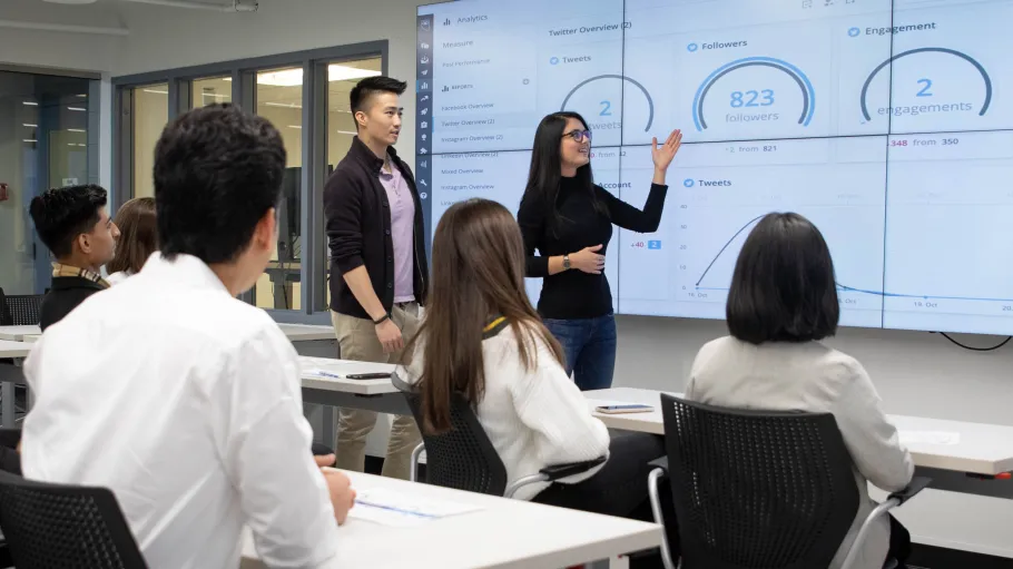 Students presenting in front of the class with a professor.