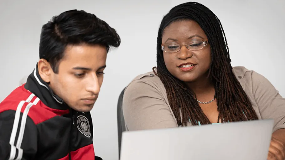 A staff member helping a student with something on a laptop