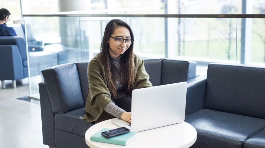 A female student working on her laptop in a GBC common area