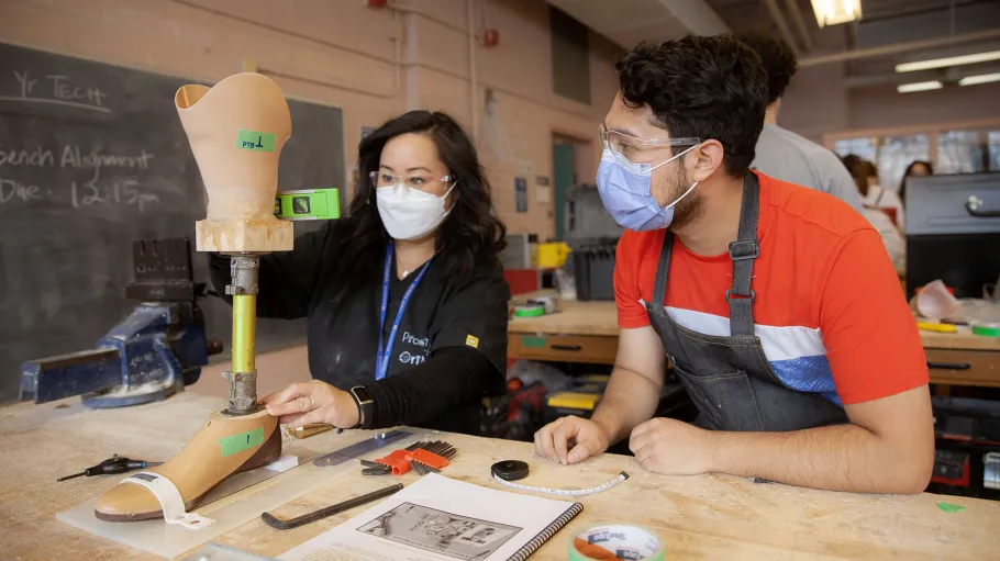 Faculty advises a male Orthotic/Prosthetic Technician (S102) student in the lab as he designs a prosthetic limb.