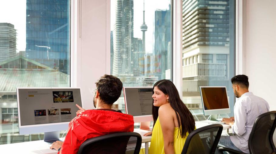 3 students in a computer lab with cityscape in the foreground.