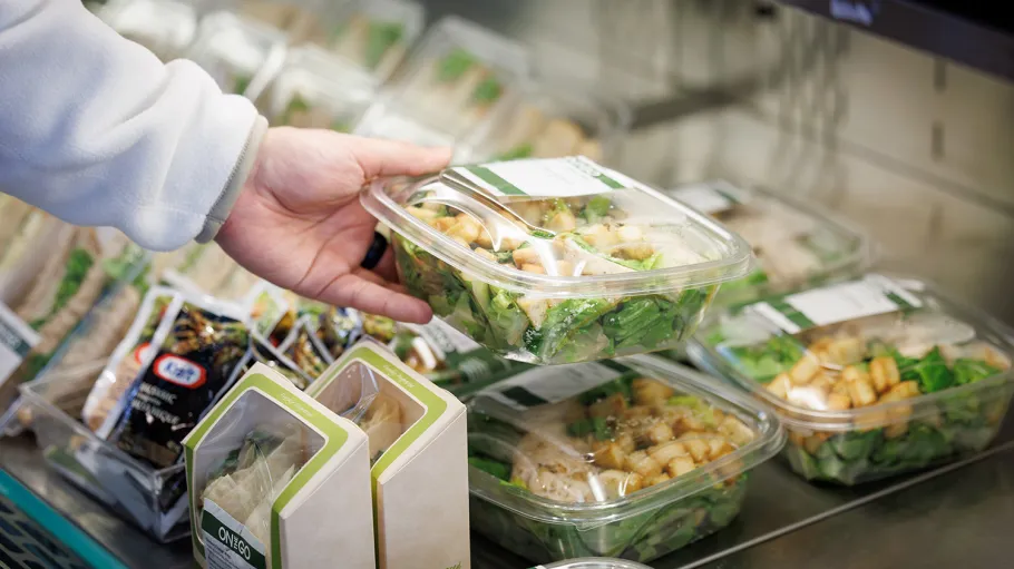 Person picking a packaged salad from a cooler