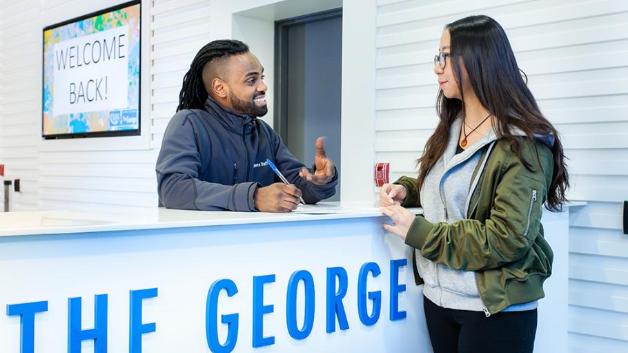 A front desk worker welcoming a resident at The George student residence