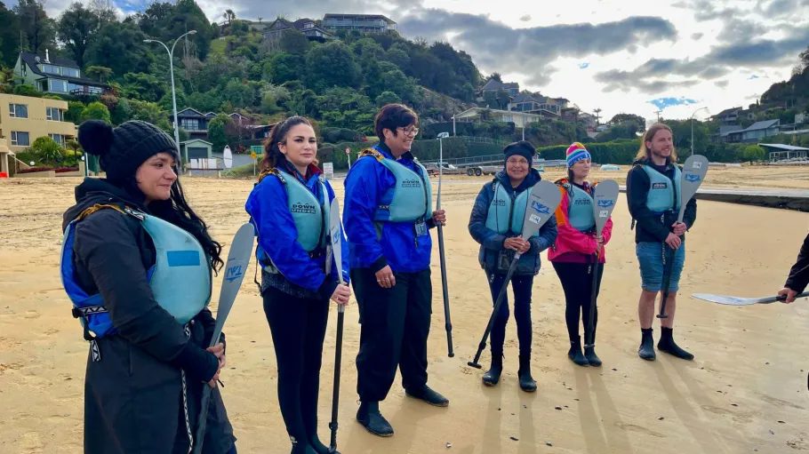 students on the beach holding paddles