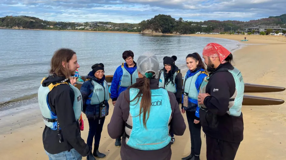 People on a beach in life jackets standing in a circle