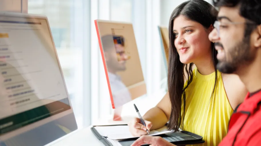 two people looking at a desktop computer