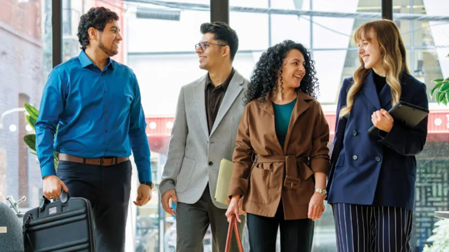 Four newcomer students walking in a hall, smiling and talking