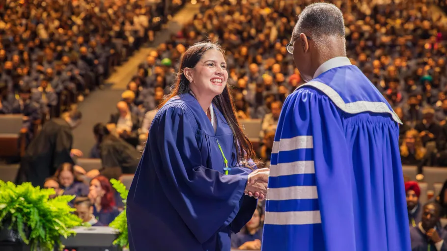 A GBC graduate on stage shakes President Fearon's hand