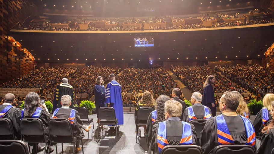 Dr Gervan Fearon on stage with graduate, Convocation 2025