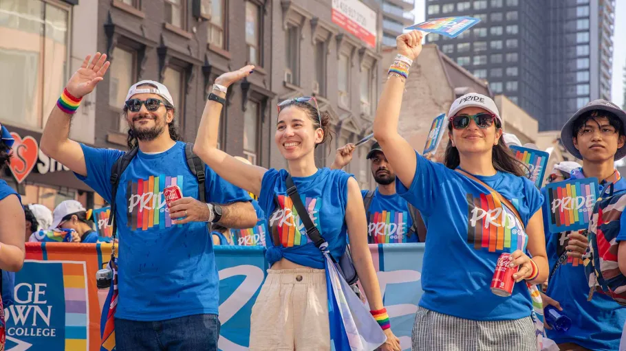 Four Pride parade marchers waving